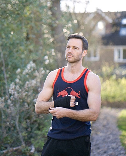 Scott McQuillan, personal trainer, standing outdoors in a training vest